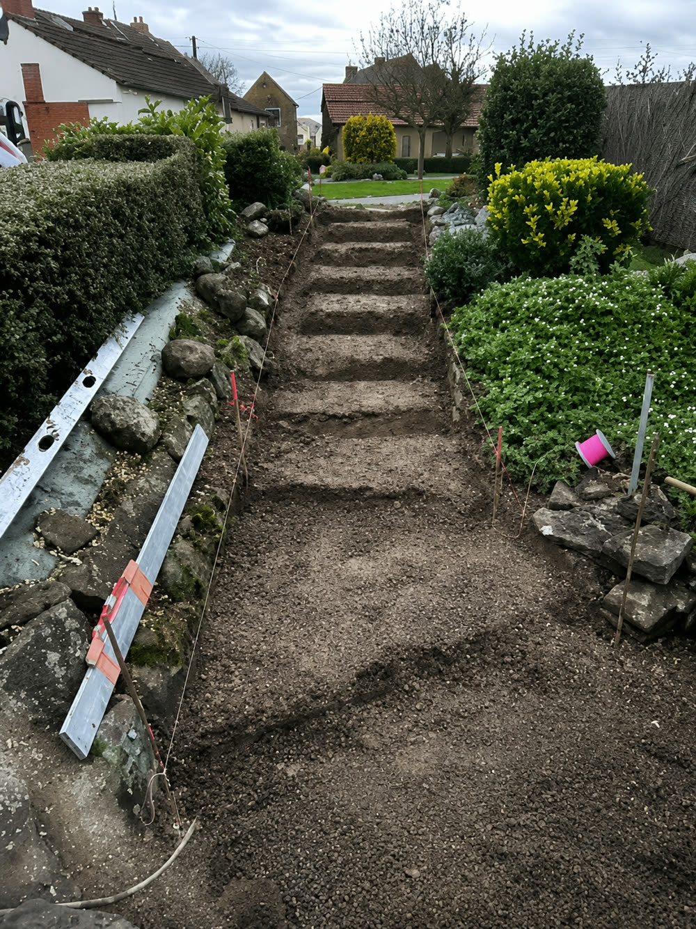 Escalier de jardin en cours de terrassement, marches en terre piquetées et cordeaux tendus